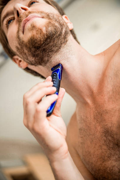 istock Handsome young man shaving with electric razor 1200734867