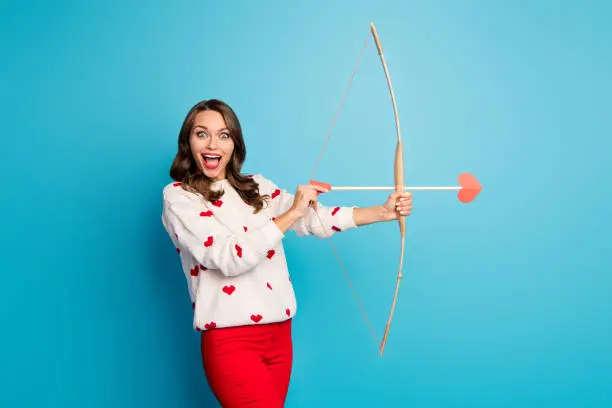 Portrait of her she nice attractive lovely pretty amazed astonished cheerful cheery girl shooting arrow, amorous goal isolated on bright vivid shine vibrant blue color background