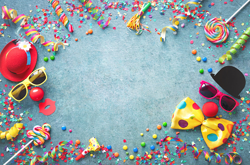 Colorful carnival or party background streamers and confetti and funny faces formed from bow tie, hat, eyeglasses and lips