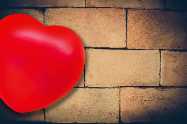 istock Red heart ball on old and dirty clay brick wall on background. 1200746775