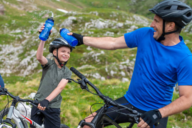 istock Father and son squirting water during a cycling water break 1200748122
