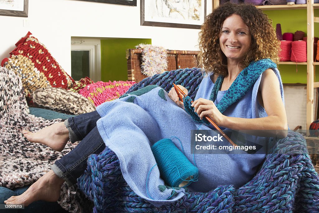 Kobieta siedzi w fotelu Robić na drutach - Zbiór zdjęć royalty-free (Robić na drutach)