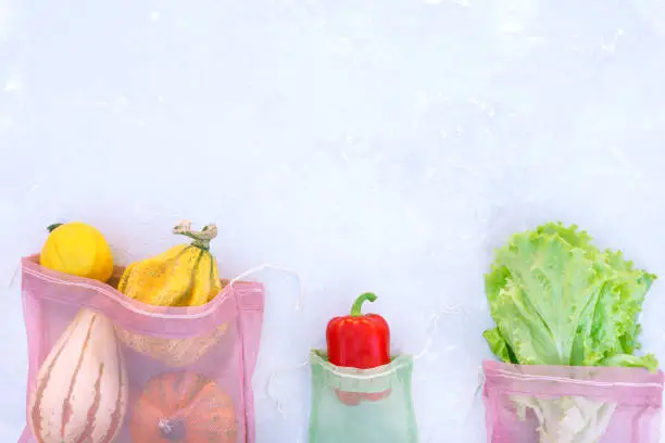 Photo of Eco bags with vegetables on a gray background.
