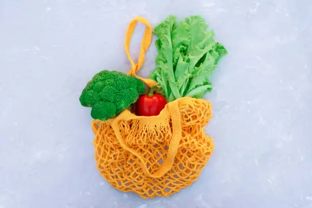 Photo of Eco bag with healthy vegetables on a light background.