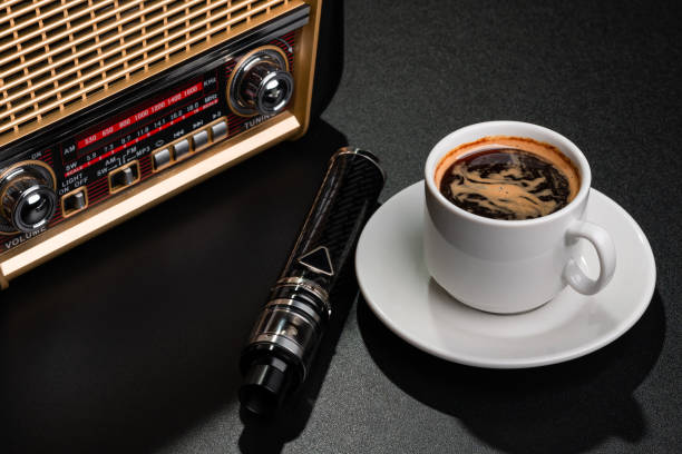 receptor de rádio, xícara de café e cigarro eletrônico na superfície preta - fresh coffee audio - fotografias e filmes do acervo