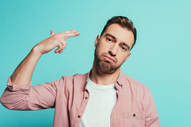 istock confused man with hand gun gesture, isolated on blue 1200755681