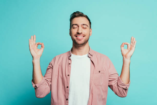 istock cheerful man with closed eyes showing om gesture, isolated on blue 1200755690