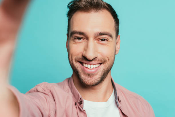 istock handsome smiling man taking selfie, isolated on blue 1200755702