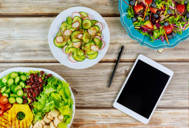 istock Various salads with tablet and pen on wooden table. 1200762169