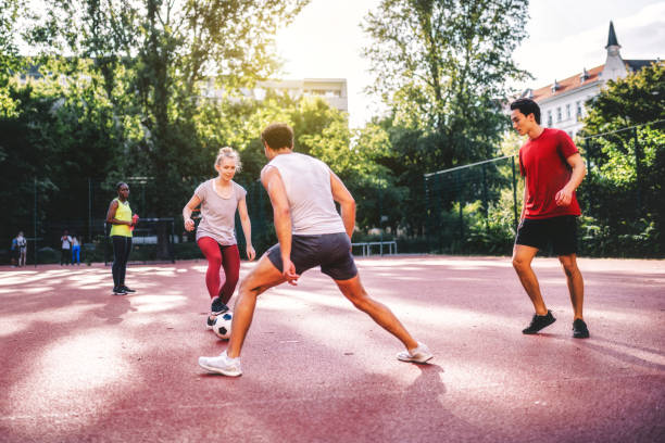 junge sportler und frauen, die auf dem hartplatz fußball spielen - mixed age stock-fotos und bilder