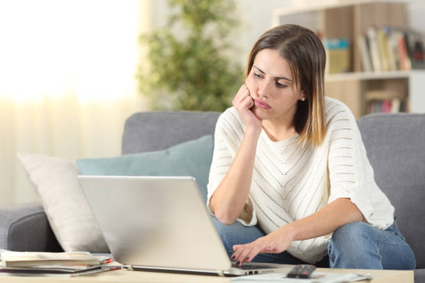 istock Bored woman checking laptop online content at home 1200762328