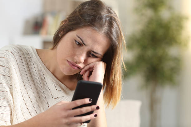 istock Bored girl holding smart phone at home 1200762359