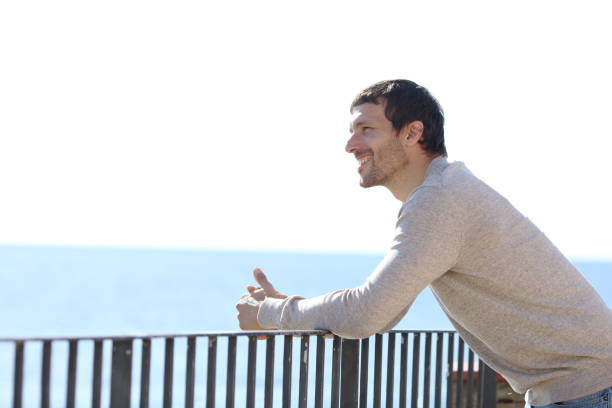 istock Happy man contemplating views from a balcony on the beach 1200762434
