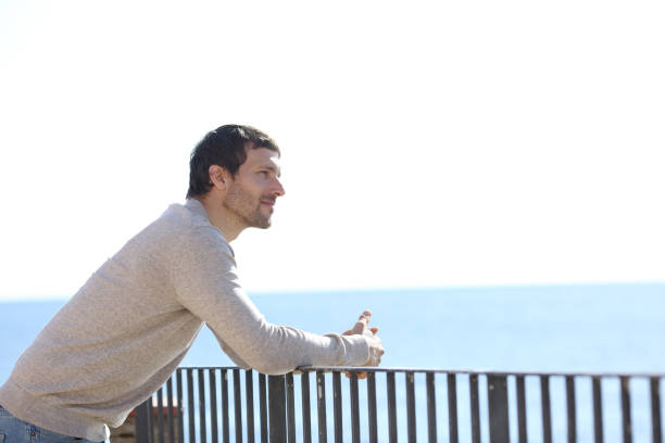 istock Serious man contemplating views from a balcony on the beach 1200762449
