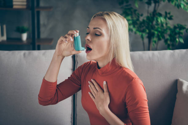 Profile photo of unhealthy pretty blond lady suffering allergy holding inhaler breathing in feel better sitting couch wear orange pullover shirt living room indoors Profile photo of unhealthy pretty blond lady suffering allergy holding, inhaler breathing in feel better sitting couch wear orange pullover shirt living room indoors allergy medicine photos stock pictures, royalty-free photos & images