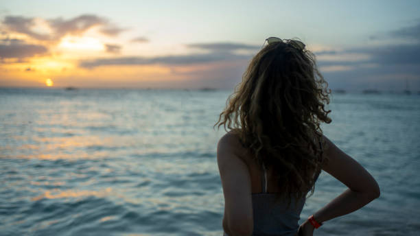 istock Woman watching the sunset on the beach 1200764278