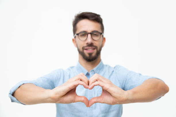 istock Cheerful young man showing hand heart gesture 1200769069