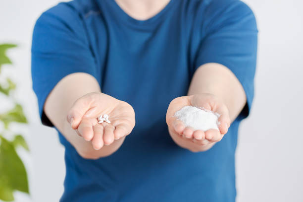 istock hands holding sugar and saccharin pills 1200770939