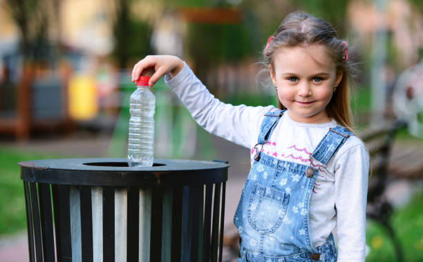 petite fille jetant la bouteille dans la poubelle. concept d'écologie - packaging recycling bottle plastic photos et images de collection