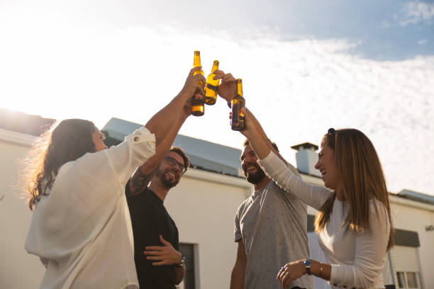 istock Joyful young friends drinking beer on balcony 1200772407