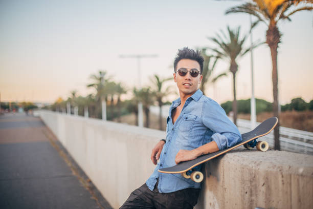 istock Guy with skateboard standing on the street 1200772531