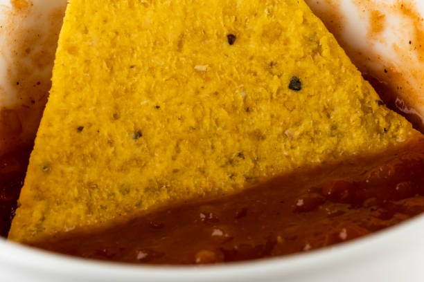 One triangular corn chips with spicy taco sauce in a plate