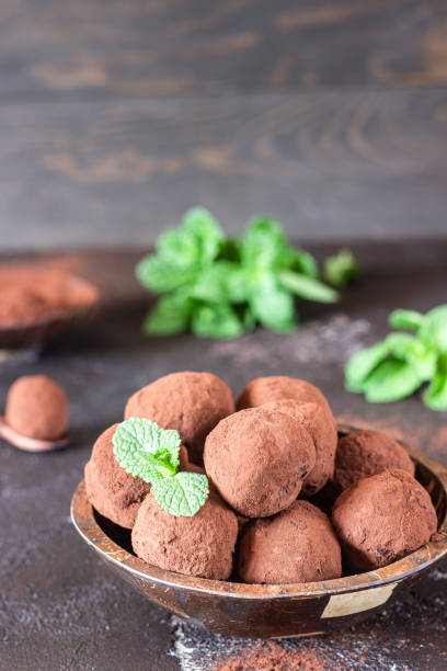 istock Dark chocolate truffles candy with raw cocoa powder and mint, dark brown stone background. 1200773653