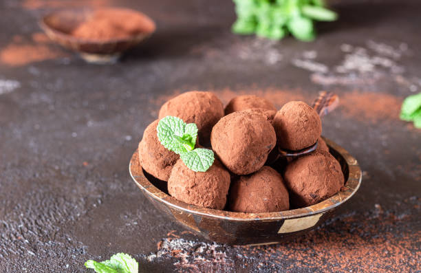 istock Dark chocolate truffles candy with raw cocoa powder and mint, dark brown stone background. 1200773655