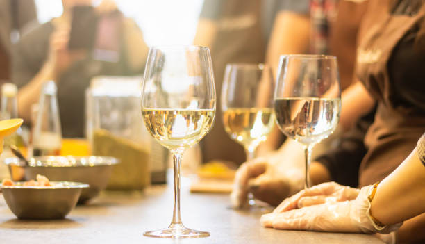 освежающее белое вино в бокалах, стоящее бок о бок на столе со свечой на солнце, размытый фон. - toast women white horizontal стоковые фото и изображения