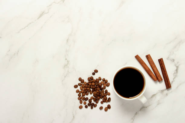 istock Cup with coffee, coffee beans and cinnamon sticks on a marble table. Flat lay, top view 1200774209