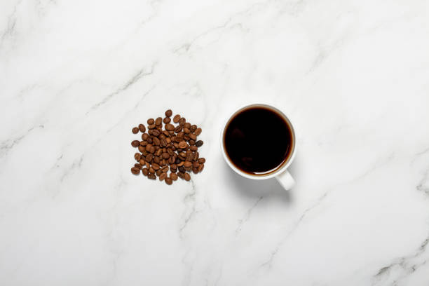 istock Cup with coffee and coffee grains on a marble table. Concept breakfast, black coffee, coffee for the night, insomnia. Flat lay, top view 1200775728