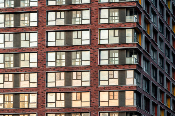 istock Brick facade of a residential multi-storey building with large windows. Modern architecture. Real estate in a big city. Background from the wall of the house. 1200775922