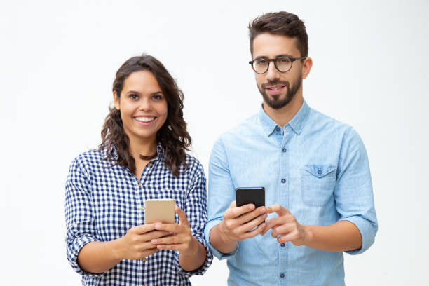 istock Cheerful young couple using smartphones 1200778091