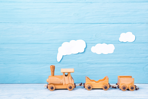 Kids background, toy wooden train with steam on a light blue wooden background