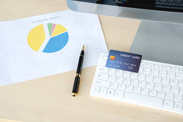 istock Credit card ready for payment on the keyboard and the different graphs on paper. 1200778865