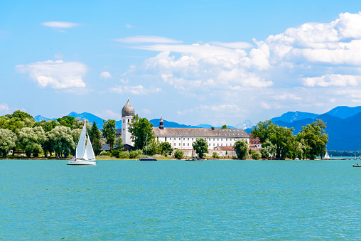 Lake Chiemsee with a boat, sailboat, church, blue sky. clouds. Bavaria, Germany