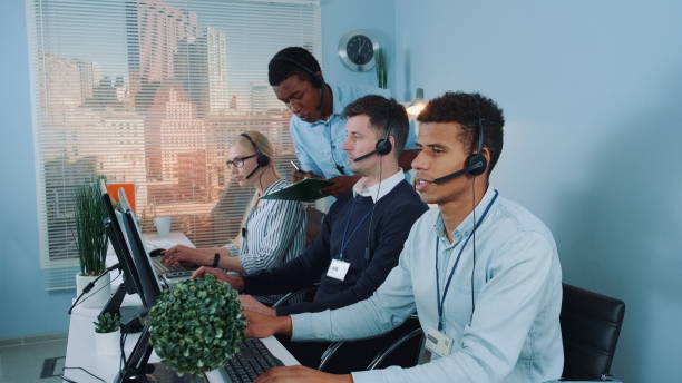 istock Black phone operator helping his colleague in call center 1200785870