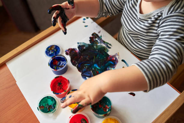 istock A small boy draws with bright colors with his fingers. 1200786233