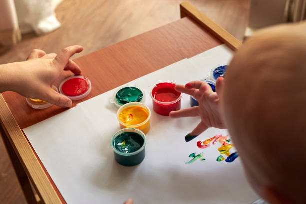 istock A small boy draws with bright colors with his fingers. 1200786239