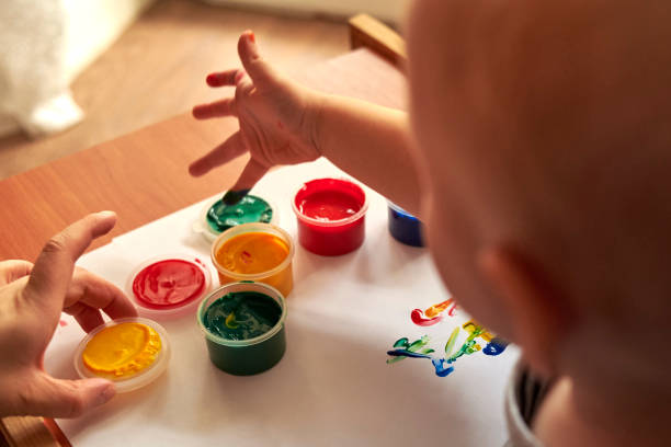istock A small boy draws with bright colors with his fingers. 1200786267