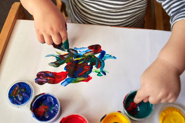 istock A small boy draws with bright colors with his fingers. 1200786756