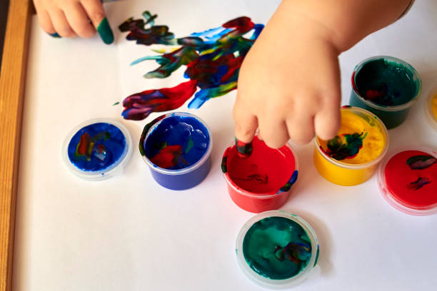 istock A small boy draws with bright colors with his fingers. 1200786765