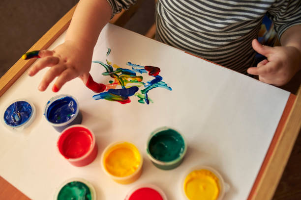 istock A small boy draws with bright colors with his fingers. 1200786778