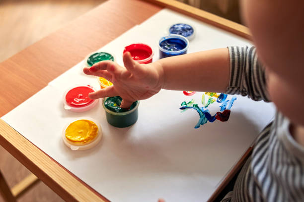 istock A small boy draws with bright colors with his fingers. 1200786790