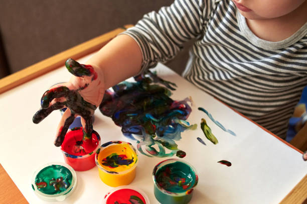 istock A small boy draws with bright colors with his fingers. 1200786800