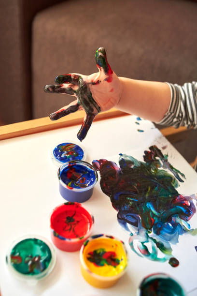 istock Hands of a child who paints with bright finger paints 1200786882