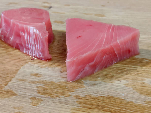 świeży, różowy filet z tuńczyka ahi rozpakowany na drewnianej bambusowej desce do krojenia - prepared ahi tuna seared portion zdjęcia i obrazy z banku zdjęć