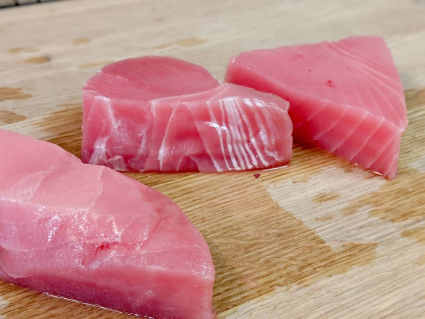 świeży, różowy filet z tuńczyka ahi rozpakowany na drewnianej bambusowej desce do krojenia - prepared ahi tuna seared portion zdjęcia i obrazy z banku zdjęć