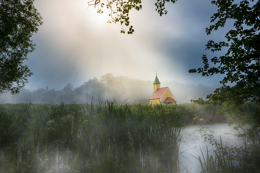 sunbeam over little chapel in the field, behind lake in Bavaria, Germany