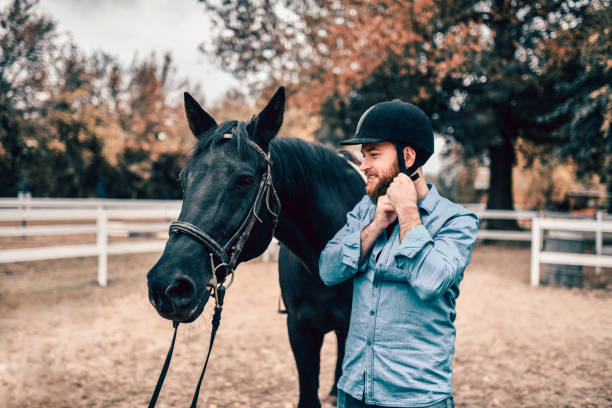 istock Male Preparing To Ride His Black Mare 1200796736
